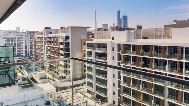 Un edificio moderno con diversi balconi e vista sullo skyline cittadino, inclusa un'alta torre.