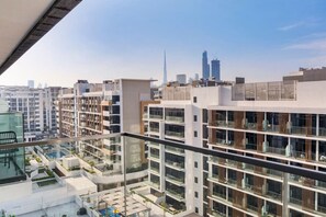 A modern apartment building with multiple balconies and a view of the city skyline, including a prominent skyscraper. - Stylish City Studio with Burj Khalifa View (Dubai)
