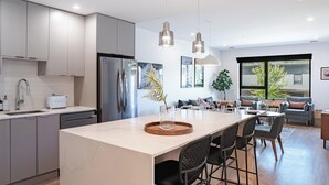 A modern kitchen with a central island, stainless steel appliances, and a dining area with a view. - Cedar and Loam by Revelstoke Vacations (Revelstoke)