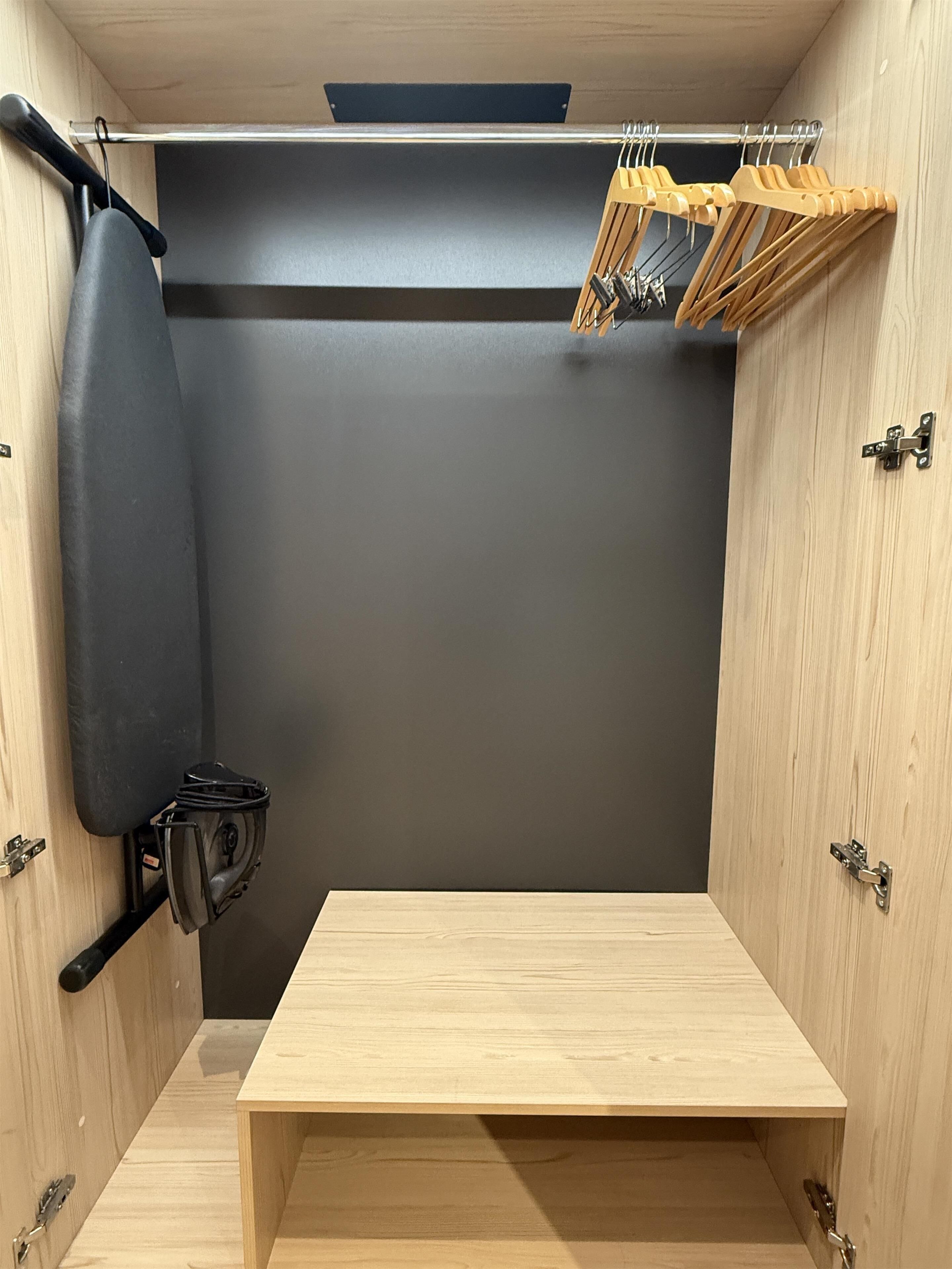 A compact room with a wooden table, a black punching bag, and a clothes rack with hangers.