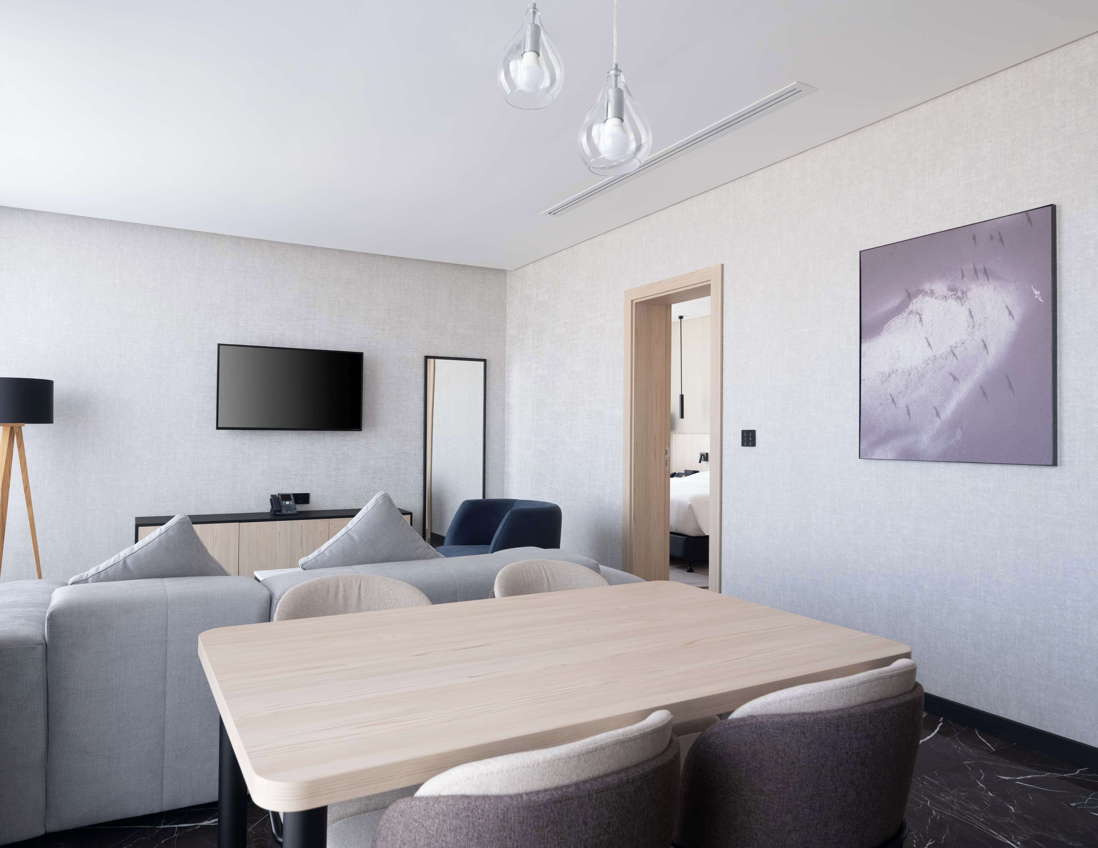 Ein modernes Hotelzimmer mit Essbereich, Flachbildfernseher, großem Spiegel und einem Bild an der Wand.