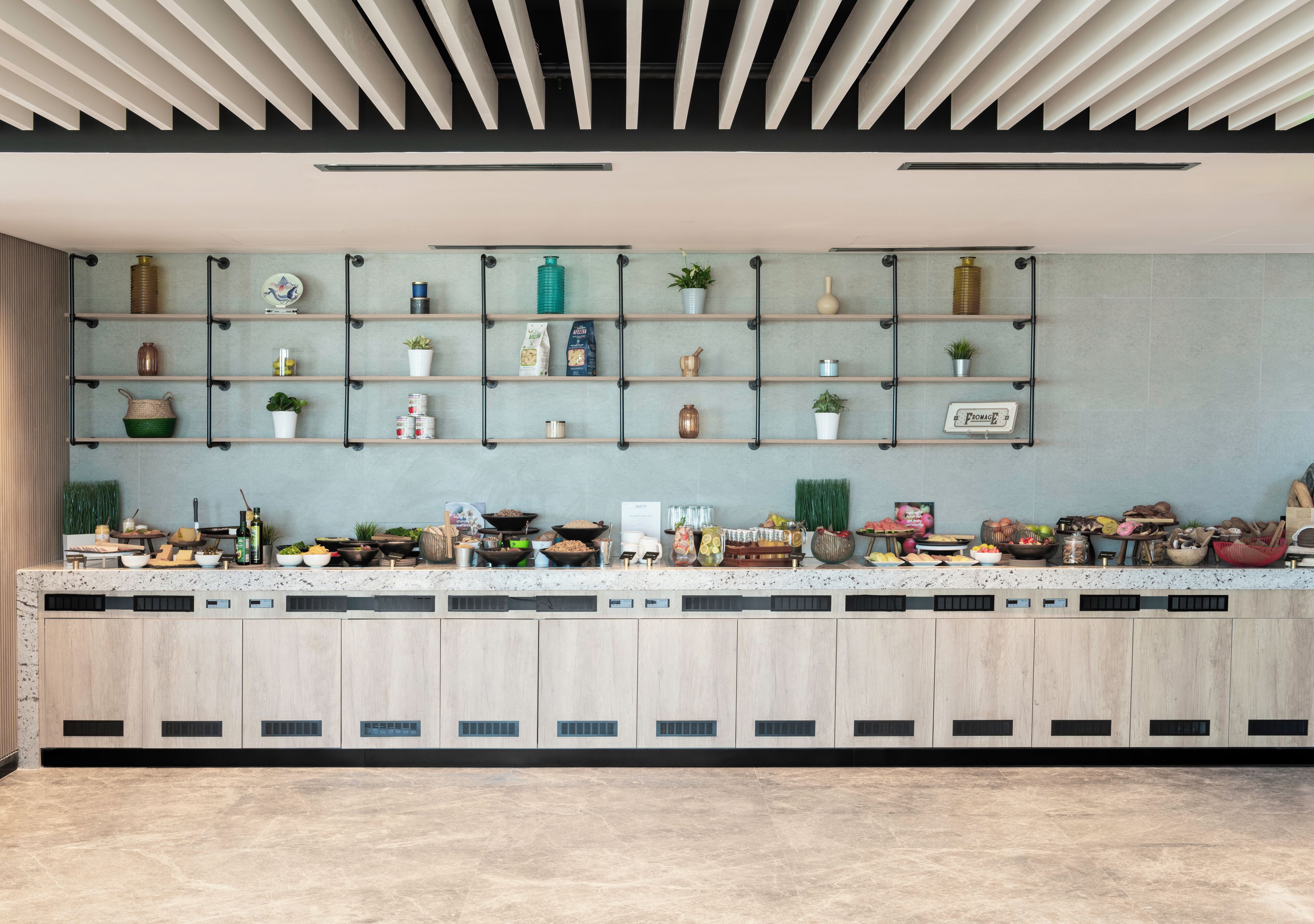 Uma cozinha moderna com ilha integrada, prateleiras abertas exibindo diversos utensílios de cozinha e teto com um design original de ripas.
