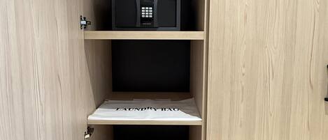 A wooden cabinet with a microwave on the top shelf and a pair of shoes on the bottom shelf.