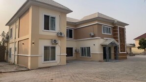 A two-story house with a paved driveway and multiple windows. - Travellers Homely (Ado Ekiti)