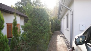 A narrow pathway leading to a white building with a tiled roof.