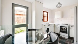 Una cocina compacta con comedor, lavadora, estufa y ventana.