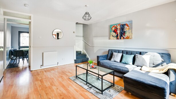 Una sala de estar moderna con un sofá azul, una mesa de centro de vidrio y una escalera que lleva a otra habitación.