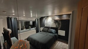 A modern bedroom with a large bed, a moon mural on the wall, a vanity with a mirror, and a ceiling light fixture. - Cozy Blackpool Retreat With 3 Bedrooms (Blackpool)
