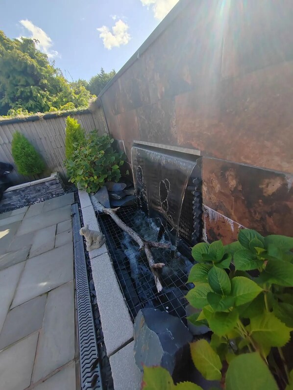 A rooftop garden with a water feature, stone steps, and potted plants. - Cozy Blackpool Retreat With 3 Bedrooms (Blackpool)