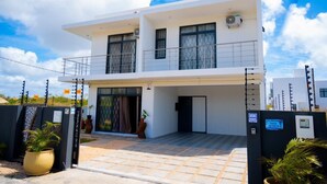 A modern two-story building with a flat roof, large windows, and a balcony. - Villa boulevard Paradise ideal for relaxing at will with family or friends (Grand Baie)