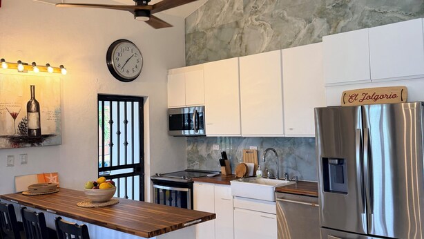 A modern kitchen with a central island, stainless steel appliances, and a ceiling fan. - Sunny Villa Mar Chiquita, WE HAVE WATER  & Game room-beach hopping paradise (Tierras Nuevas Poniente)