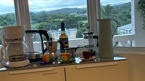 A kitchen counter with coffee-making equipment and cups, overlooking a scenic view of hills and buildings. - Sunny Villa Mar Chiquita, WE HAVE WATER  & Game room-beach hopping paradise (Tierras Nuevas Poniente)