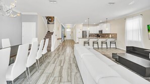 A modern kitchen with a central island, white dining chairs, and a staircase leading to another level. - EV_9036 - 9 Bed 5 Bath Villa with Screened-In Private Pool with Spillover Spa (Davenport)