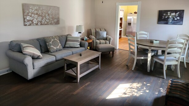 Ein Wohnzimmer mit Sofa, Sesseln, Couchtisch und Esstisch mit Stühlen.
