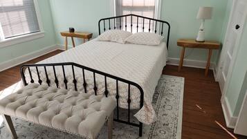 A neatly arranged bedroom with a bed, bedside tables, a bench, and a lamp.