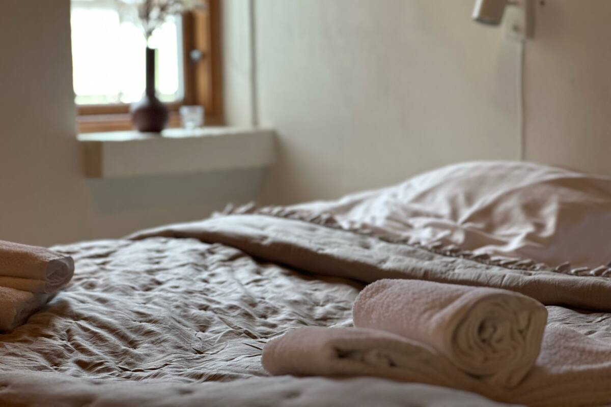 Un lit avec une serviette enroulée et une couverture.