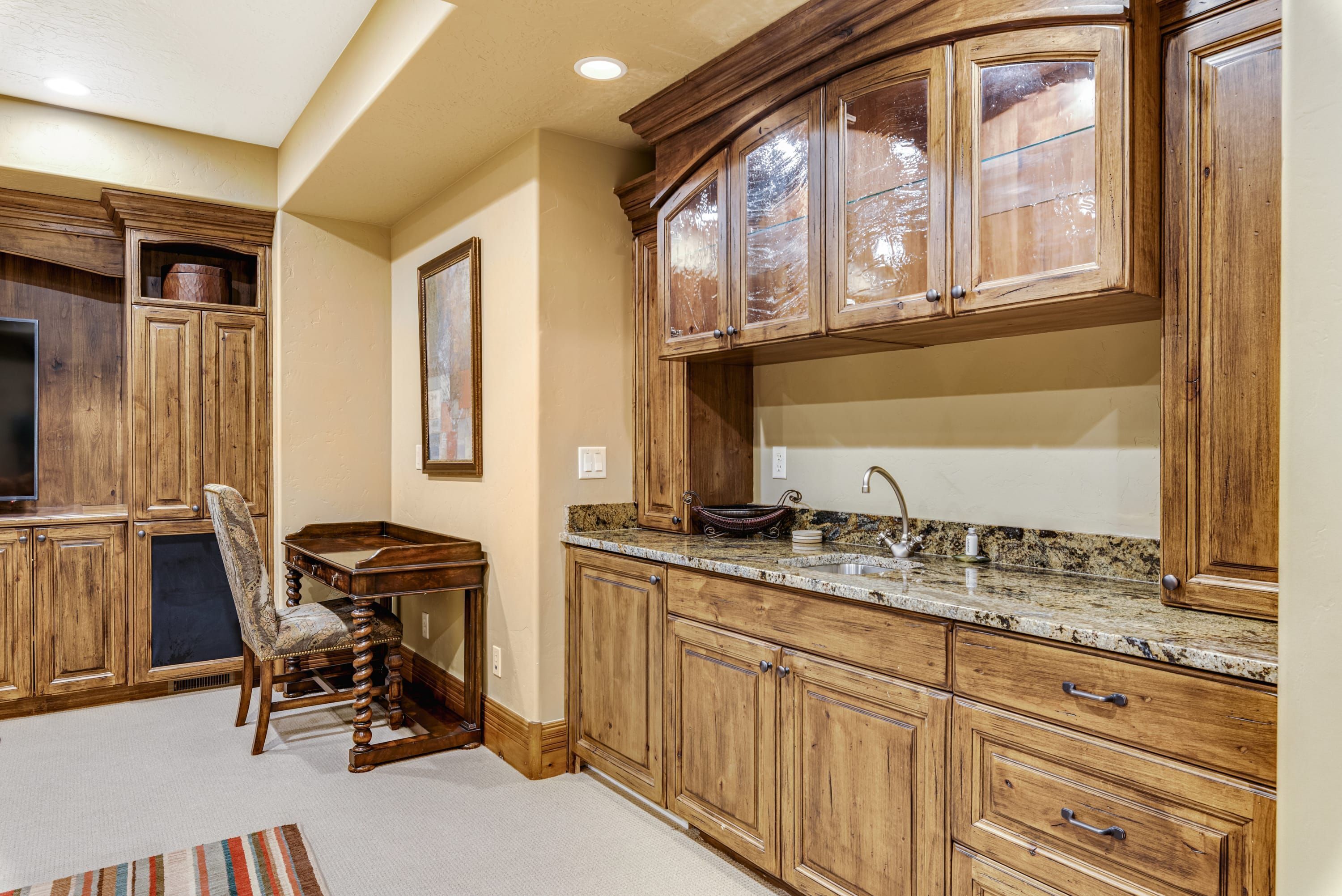 Una cocina con armarios de madera, encimera de granito y un comedor con una silla.