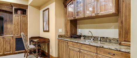 Una cocina con armarios de madera, encimera de granito y un comedor con una silla.