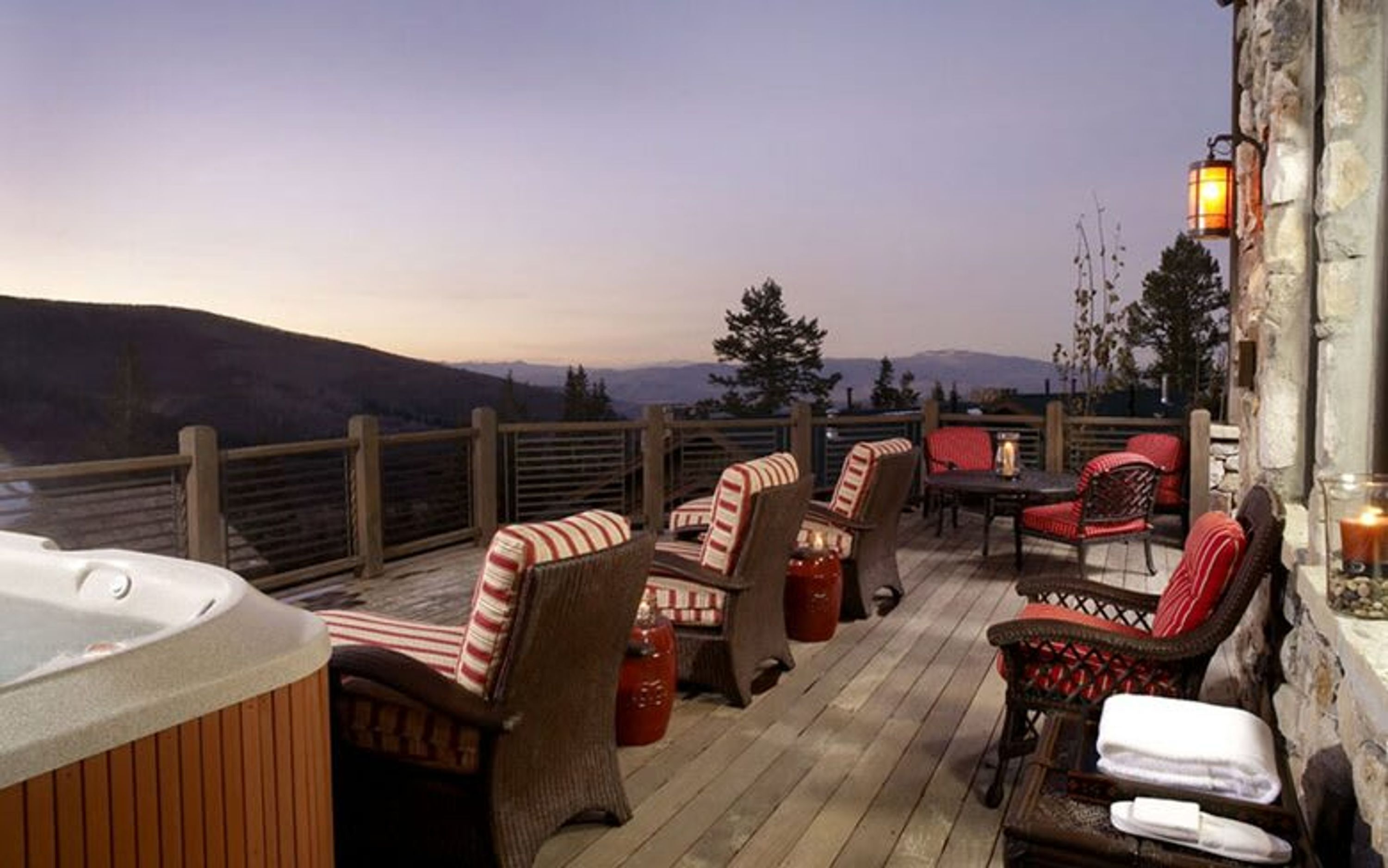A deck with outdoor seating, a hot tub, and a view of the mountains.