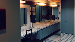 Une salle de bain moderne avec un grand miroir, deux lavabos et une chaise.