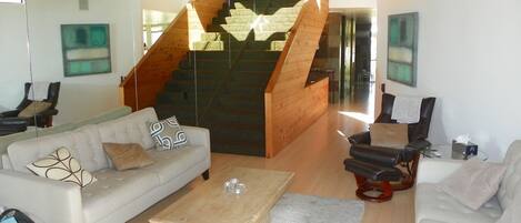 A modern living room with a staircase, two sofas, a coffee table, and artwork on the walls.