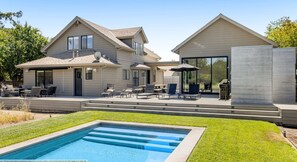 Een tweelaags huis met een zwembad, terras en een barbecueplek.