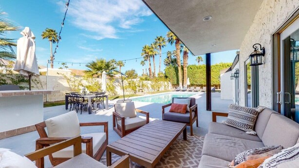 An outdoor patio with a pool, seating area, and a view of palm trees and a mountain. - Mountain View Luxury Nogales Springs Escape (Palm Springs)