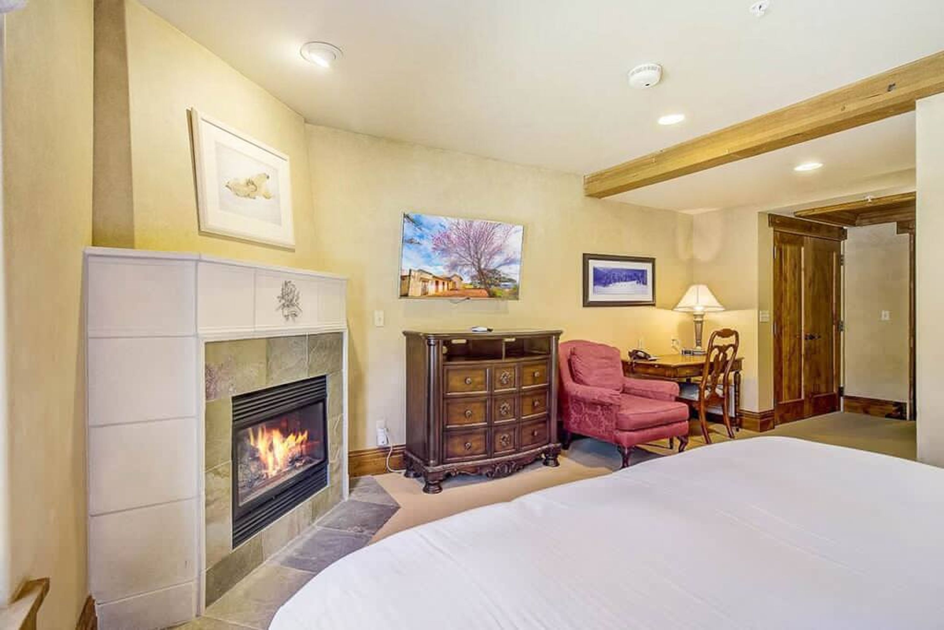 A bedroom with a fireplace, a bed, a dresser, and a chair.