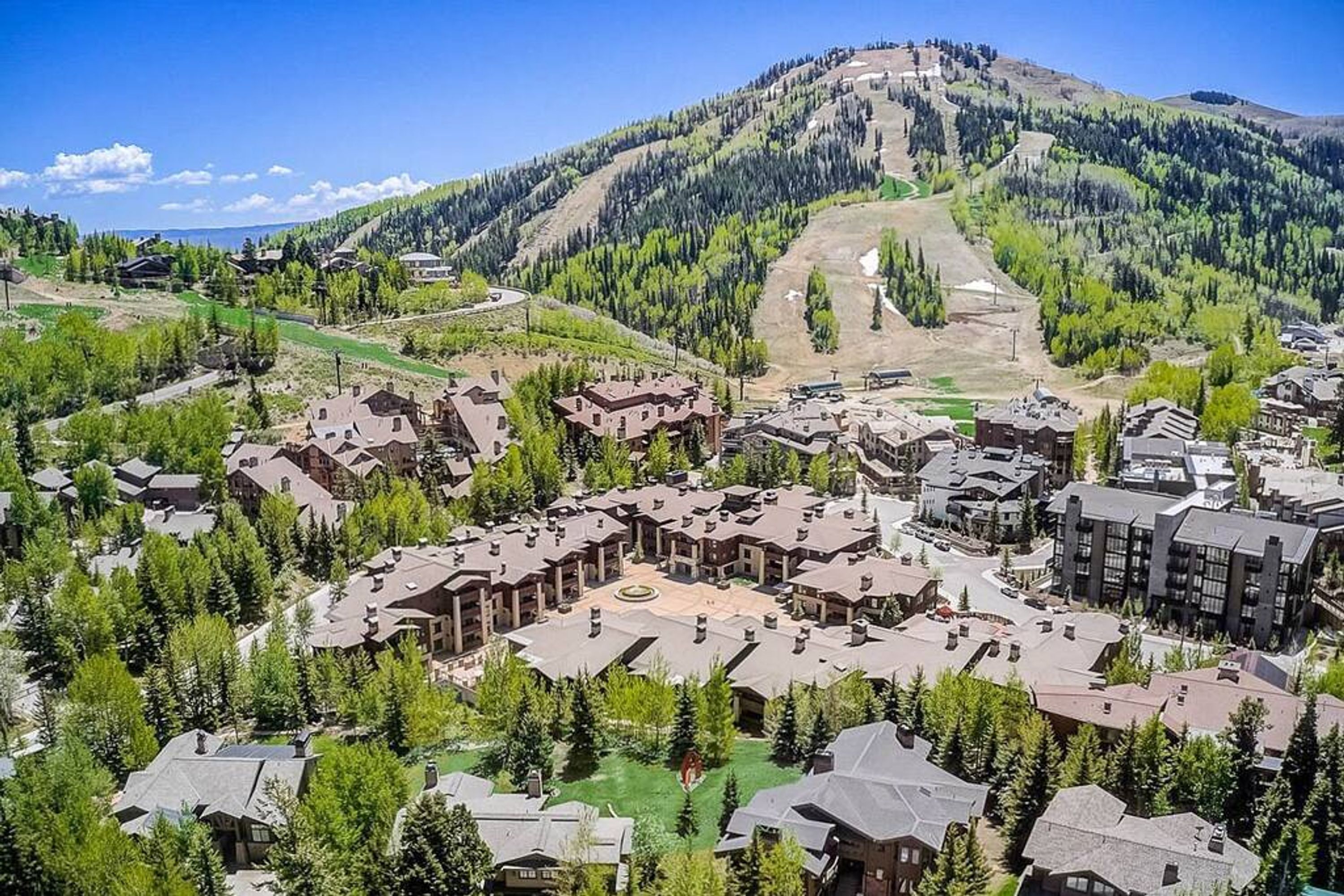 Ein Skigebiet mit mehreren Gebäuden, darunter Chalets und Apartments, umgeben von dichten Wäldern und einem Bergpanorama.