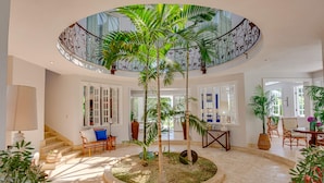 A spacious indoor area with a central circular garden, a staircase with a decorative railing, and various seating arrangements. - Villa Tortuga in Punta Cana (Punta Cana)