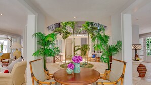 A spacious living area with a round wooden table surrounded by wicker chairs, a sofa, and potted plants. - Villa Tortuga in Punta Cana (Punta Cana)