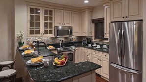 Une cuisine moderne avec des meubles de couleur claire, des appareils en acier inoxydable et un plan de travail en granit.