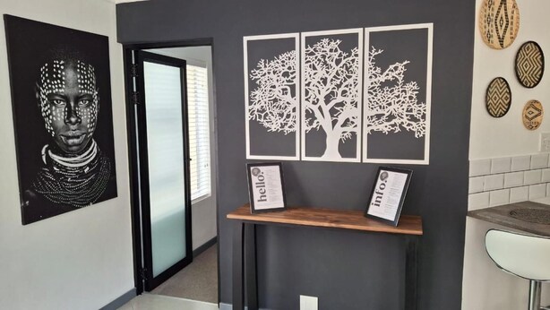 A modern interior with a black and white abstract painting, a wooden reception desk, and a white tiled wall. - Dee-ones at Witboom With Pool (Cape Town)