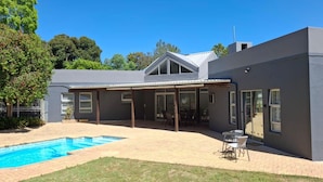 A modern house with a covered patio, a swimming pool, and a well-maintained lawn. - Dee-ones at Witboom With Pool (Cape Town)