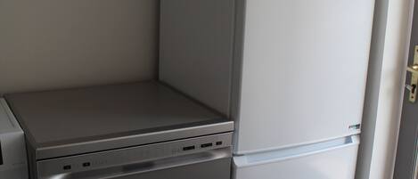 Une cuisine compacte dotée d’un lave-vaisselle encastré et d’un réfrigérateur blanc.