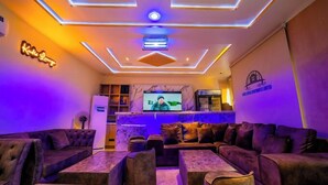 Ein modernes Wohnzimmer mit Fernseher, bequemen Sofas und einer Neonleuchtreklame an der Wand.