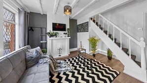 Ett modernt vardagsrum med en soffa, en öppen spis, en trappa och en tv som är monterad på väggen.