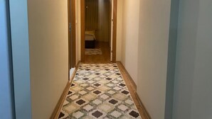 Un pasillo estrecho con piso estampado que conduce a una habitación con cama.