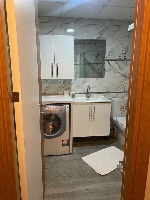 Una cocina compacta con lavadora integrada, un lavamanos y una pequeña encimera.