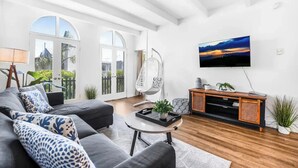 Un salon moderne avec un canapé, un fauteuil suspendu, une table basse et un téléviseur fixé au mur.