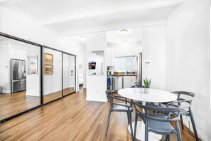 Een moderne keuken met een centraal eiland, een eethoek met een ronde tafel en stoelen, en een schuifdeur naar een andere kamer.