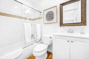 Een badkamer met een douchecabine van glas, een wit toilet en een wastafel met een spiegel.