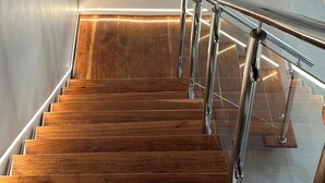 A wooden staircase with a metal handrail, leading up to a wall-mounted clock. - The Cozy and Comfy Home In Portglen (Harare)