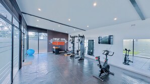 A modern gym with exercise equipment, a large mirror, and a motivational wall sign. - The Cozy and Comfy Home In Portglen (Harare)
