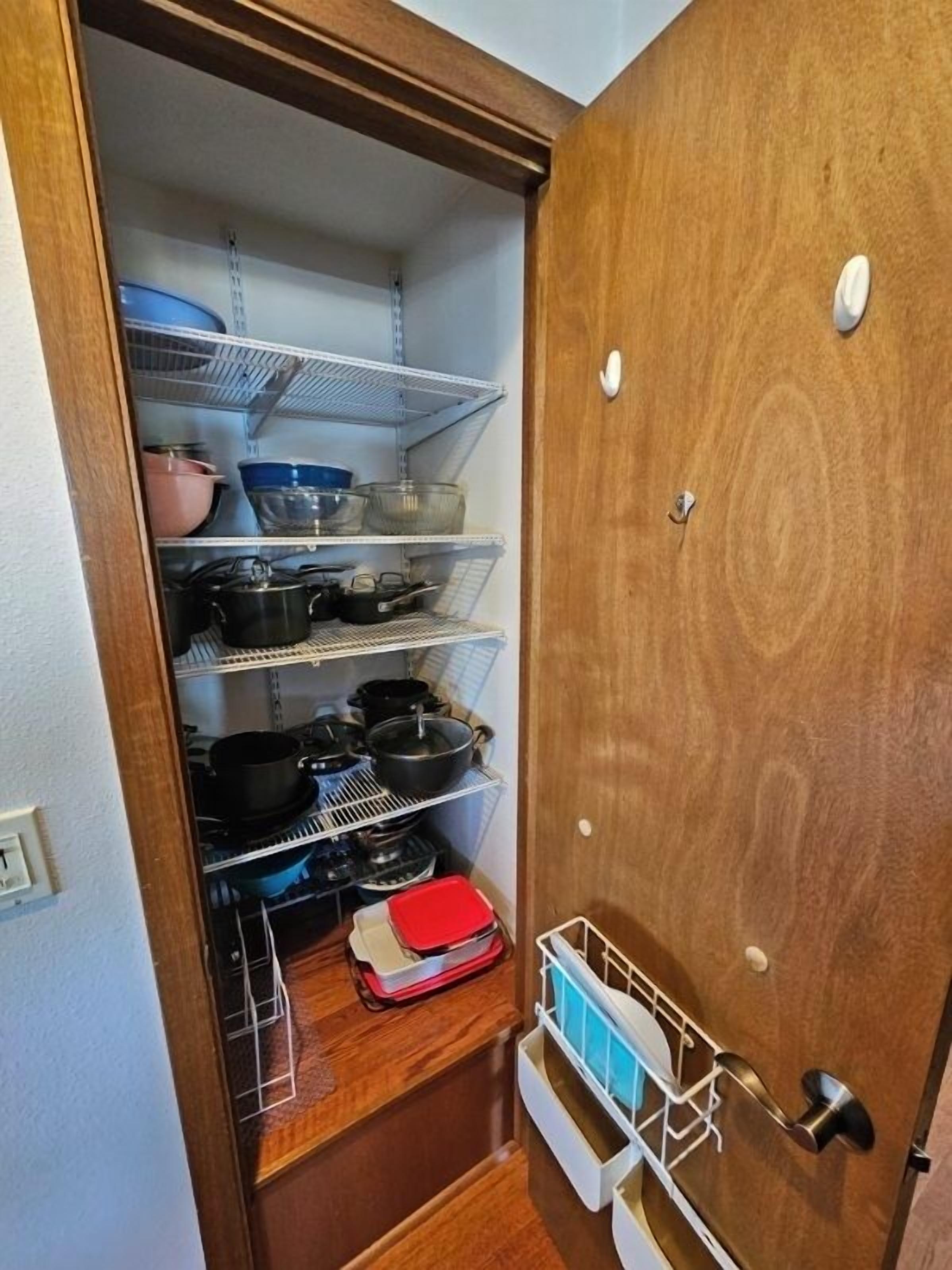 Una despensa con estantes que contienen ollas, sartenes y utensilios de cocina.