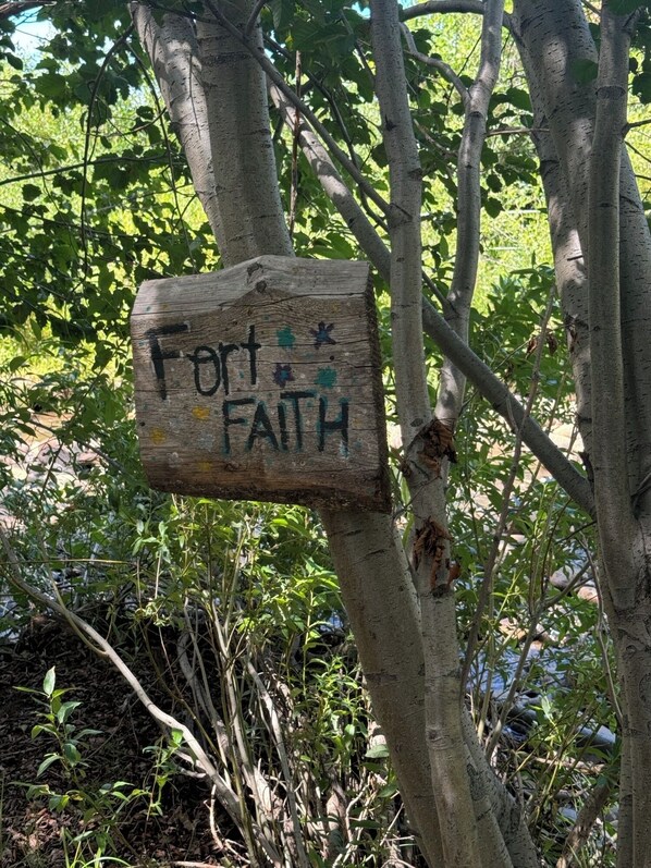 Een houten bordje met de tekst 'Fort Faith' bevestigd aan een boom.