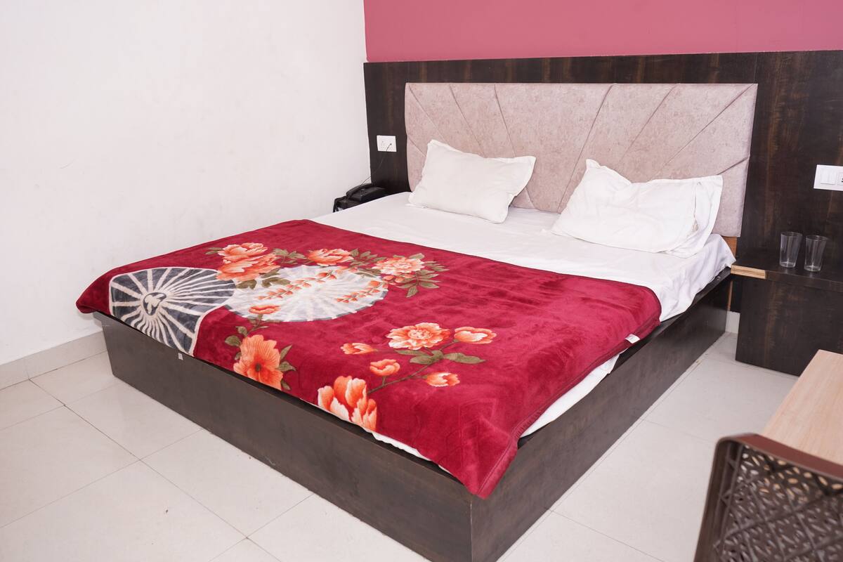 A bed with a floral bedspread, a headboard, and bedside tables.