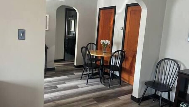 A dining area with a round table, four chairs, and a vase with flowers. There are two wooden doors and a small window. - Rhine Suite at Brickhouse Inn (Hermann)