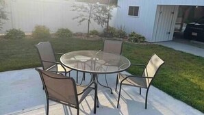 A round glass table with metal chairs in a backyard. - Blue Suite at Brickhouse Inn (Hermann)