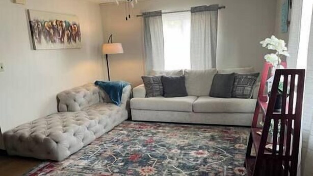 A living room with a sofa, a chair, a lamp, and a floral rug. - Roam Suite at Brickhouse Inn (Hermann)